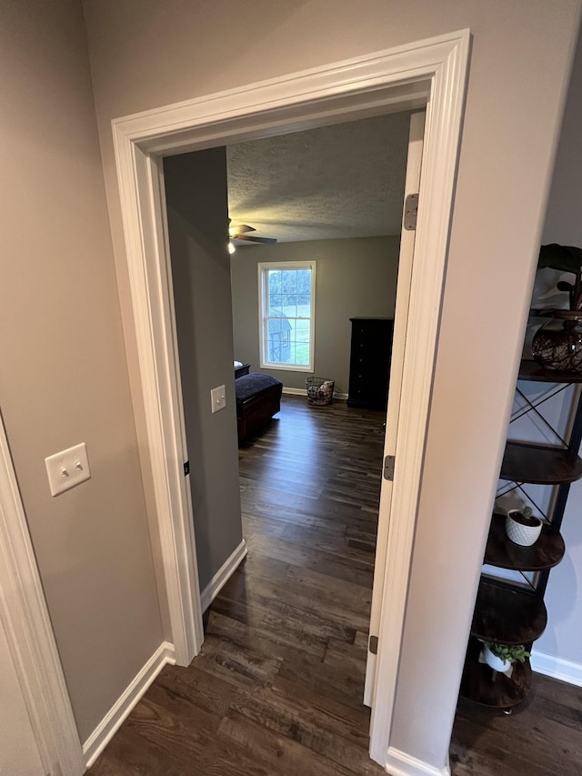 hallway featuring dark wood-type flooring and a textured ceiling