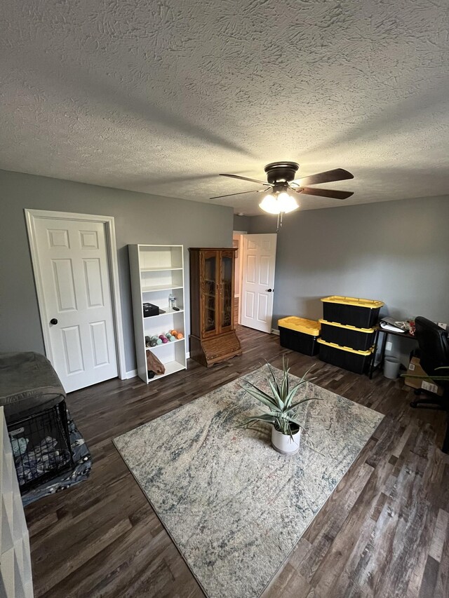 living room with ceiling fan, dark wood-type flooring, and a textured ceiling