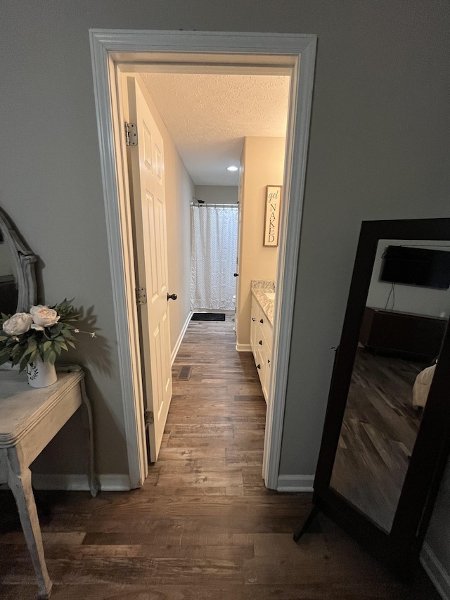 hallway with dark hardwood / wood-style floors and a textured ceiling