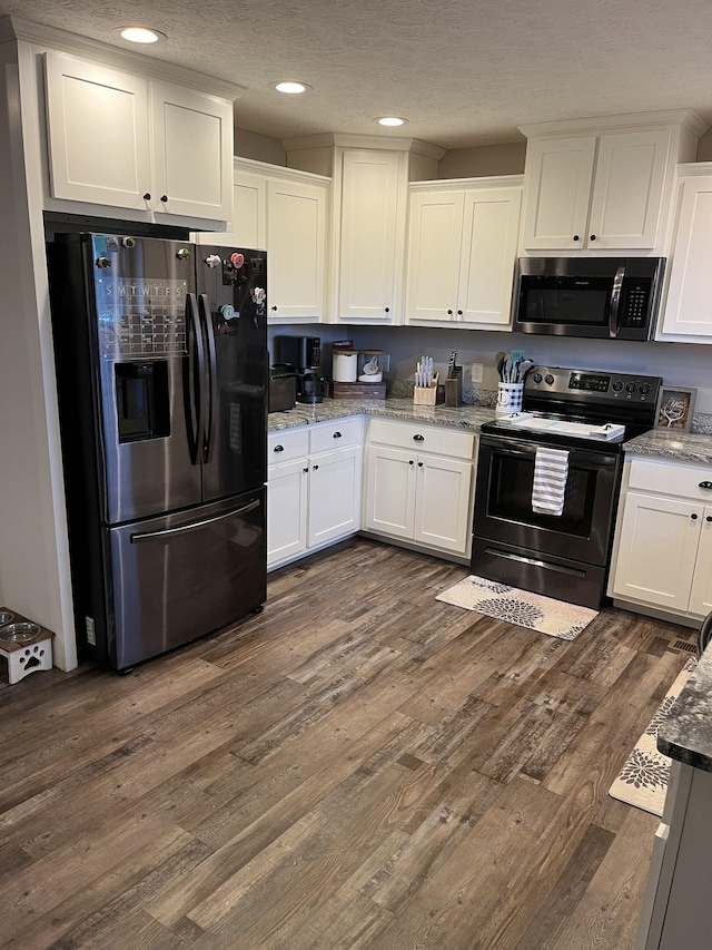 kitchen featuring a textured ceiling, appliances with stainless steel finishes, dark hardwood / wood-style floors, light stone countertops, and white cabinets