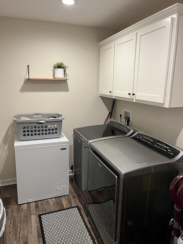 laundry room featuring dark wood-type flooring, cabinets, and washing machine and clothes dryer