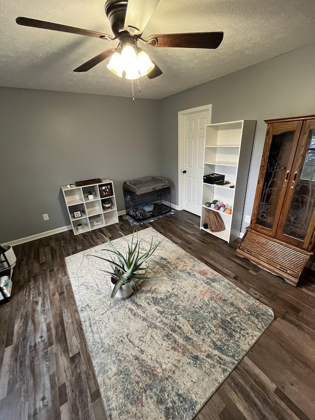 miscellaneous room with ceiling fan, dark wood-type flooring, and a textured ceiling