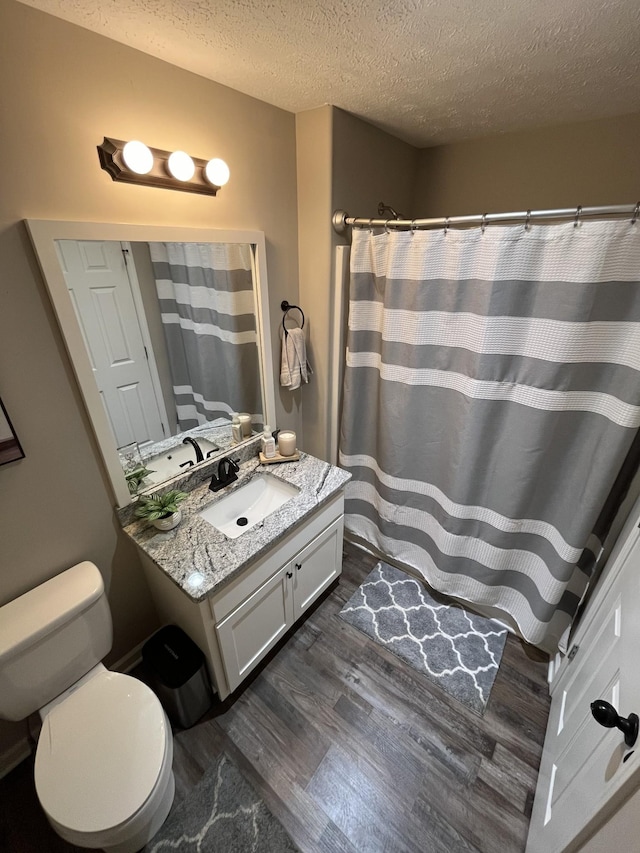 bathroom with wood-type flooring, toilet, a textured ceiling, and vanity