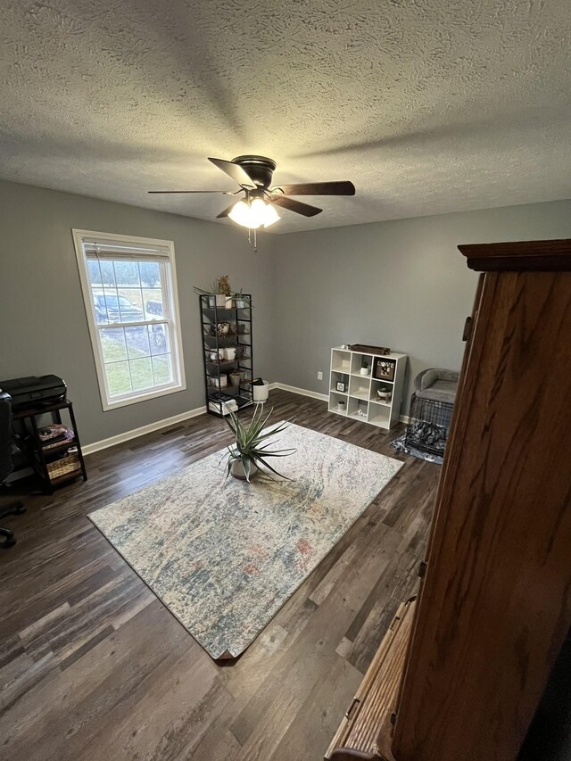 sitting room featuring ceiling fan, dark hardwood / wood-style floors, and a textured ceiling