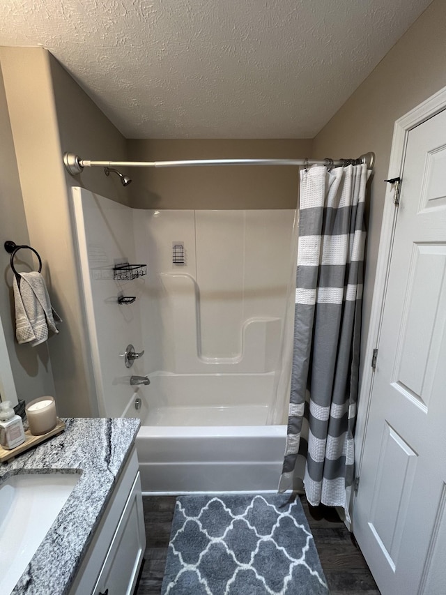 bathroom with shower / bathtub combination with curtain, vanity, wood-type flooring, and a textured ceiling