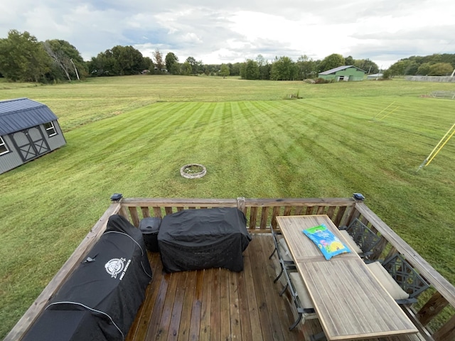 view of yard featuring a wooden deck, a fire pit, and a storage shed