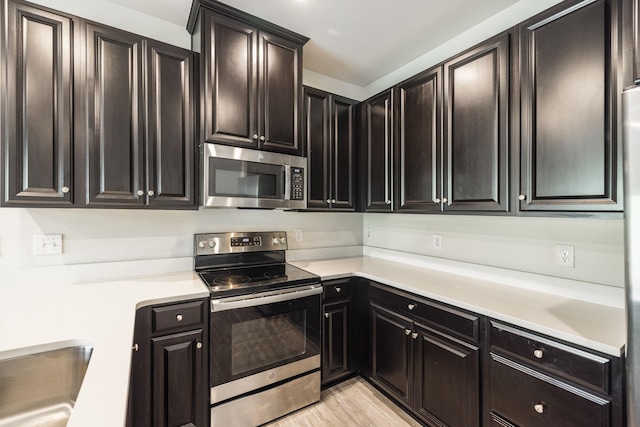 kitchen with stainless steel appliances, sink, and light hardwood / wood-style floors