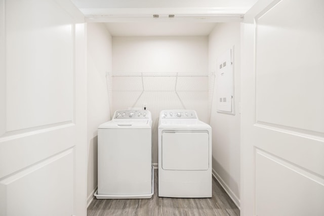 clothes washing area with washer and dryer, electric panel, and light hardwood / wood-style floors