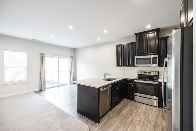 kitchen with stainless steel appliances, sink, light wood-type flooring, and kitchen peninsula