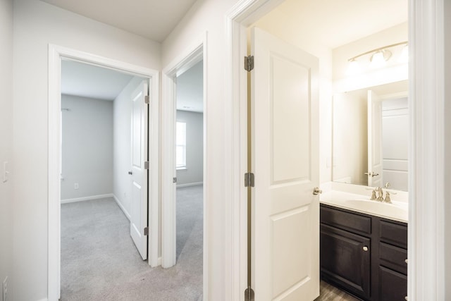 hallway with sink and light carpet