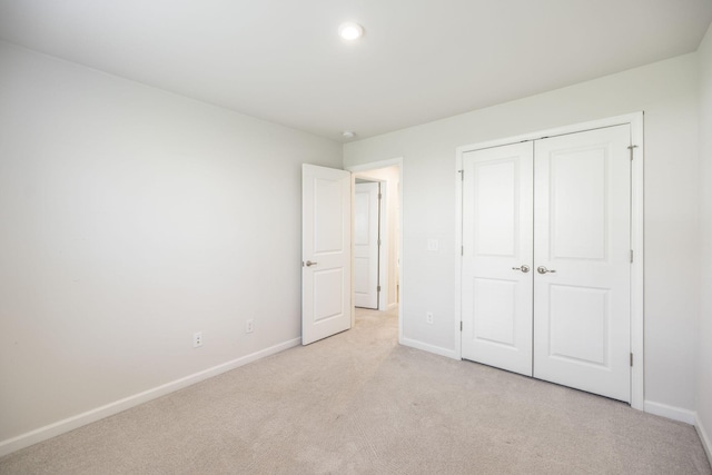 unfurnished bedroom featuring light colored carpet and a closet