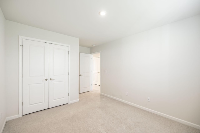 unfurnished bedroom featuring light carpet and a closet