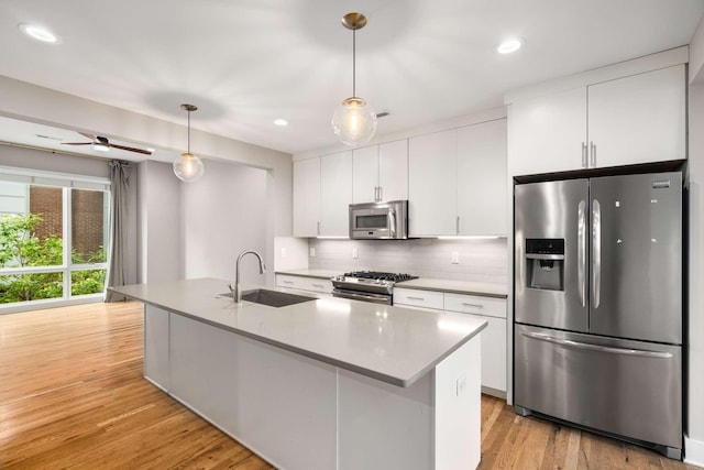 kitchen with pendant lighting, white cabinetry, an island with sink, sink, and stainless steel appliances