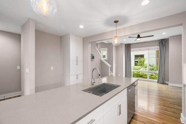 kitchen with sink, light hardwood / wood-style flooring, dishwasher, pendant lighting, and white cabinets