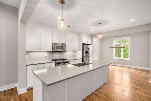 kitchen featuring stainless steel appliances, sink, pendant lighting, and a kitchen island with sink