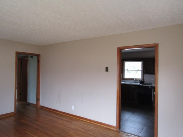 empty room featuring dark wood-type flooring, sink, and a textured ceiling