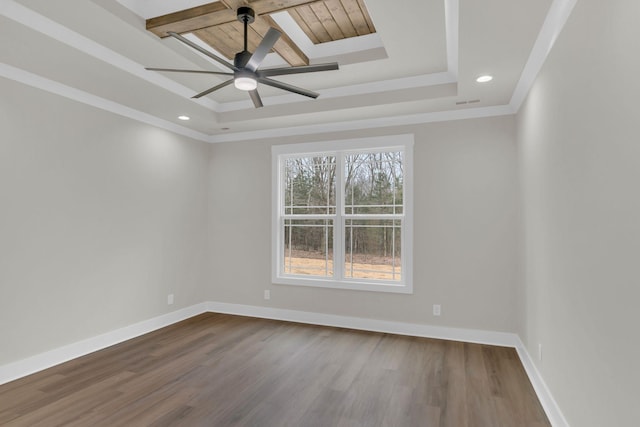 empty room with ceiling fan, ornamental molding, wood-type flooring, and a raised ceiling