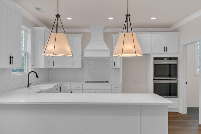 kitchen with double oven, decorative light fixtures, sink, and custom exhaust hood