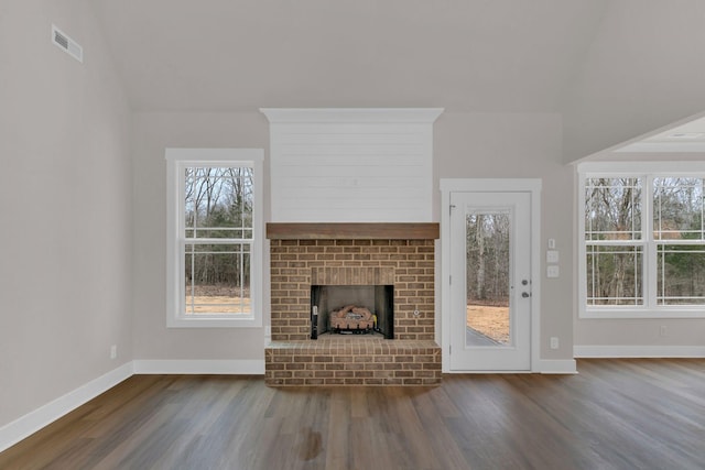 unfurnished living room with hardwood / wood-style floors and a brick fireplace