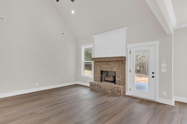 unfurnished living room featuring hardwood / wood-style flooring, high vaulted ceiling, and a fireplace