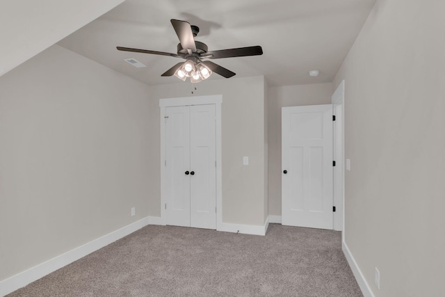 unfurnished bedroom featuring light carpet, a closet, and ceiling fan