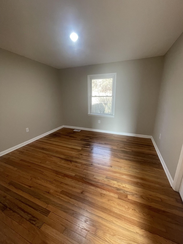 spare room featuring baseboards and wood finished floors