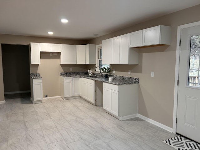 kitchen featuring marble finish floor, white cabinetry, baseboards, and a sink