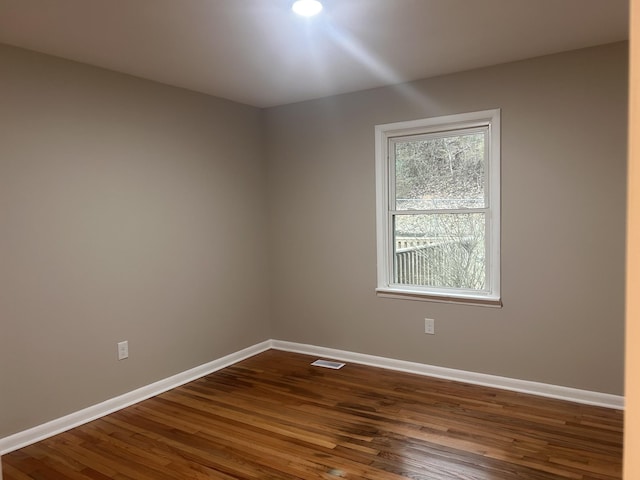 unfurnished room with visible vents, baseboards, and dark wood-type flooring