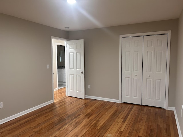 unfurnished bedroom featuring hardwood / wood-style flooring, baseboards, and a closet