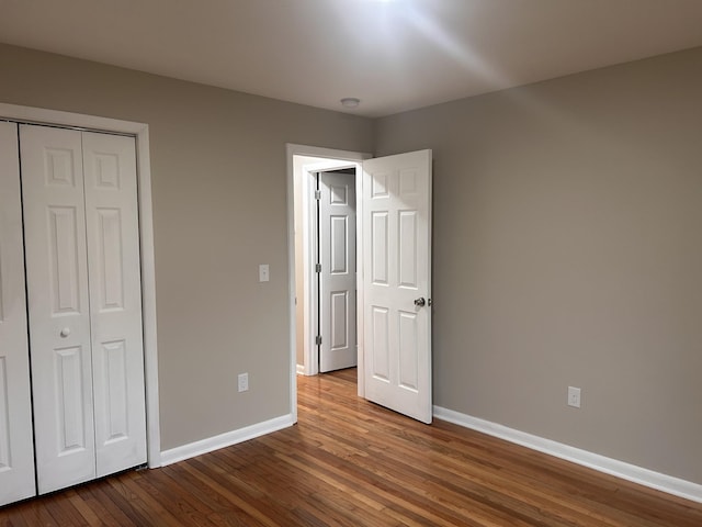 unfurnished bedroom featuring a closet, baseboards, and wood finished floors