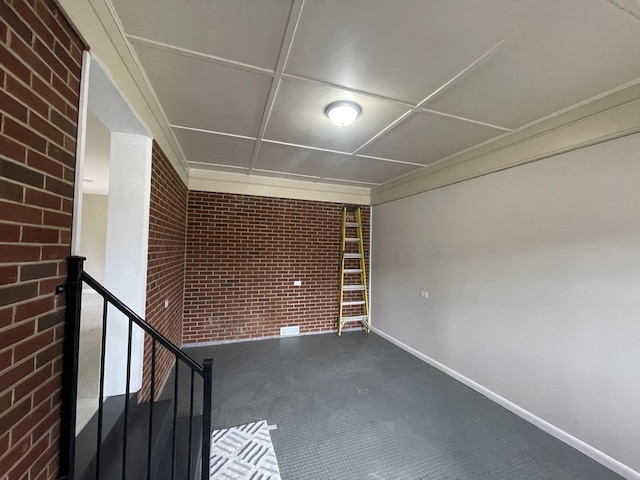 empty room featuring baseboards and brick wall