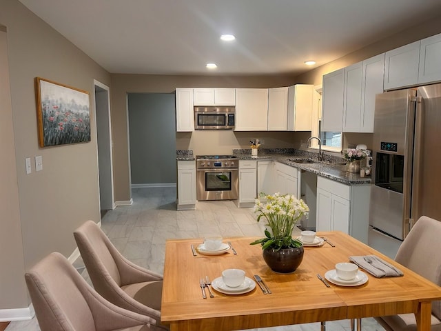 kitchen featuring recessed lighting, stainless steel appliances, marble finish floor, white cabinetry, and a sink