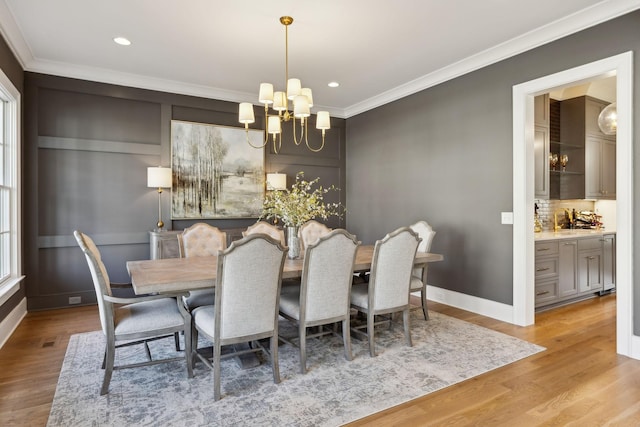 dining area featuring crown molding, sink, light hardwood / wood-style floors, and a notable chandelier