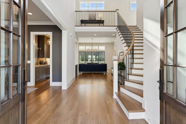 foyer entrance with an inviting chandelier, ornamental molding, french doors, and hardwood / wood-style flooring