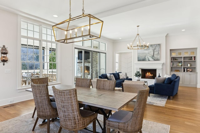 dining room with ornamental molding, a chandelier, and light wood-type flooring