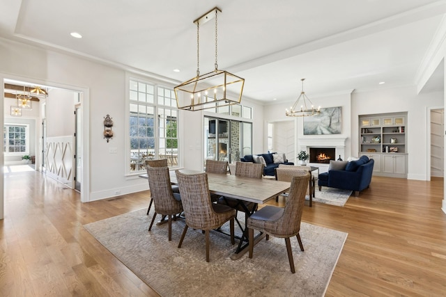 dining room featuring built in shelves, a chandelier, and light wood-type flooring