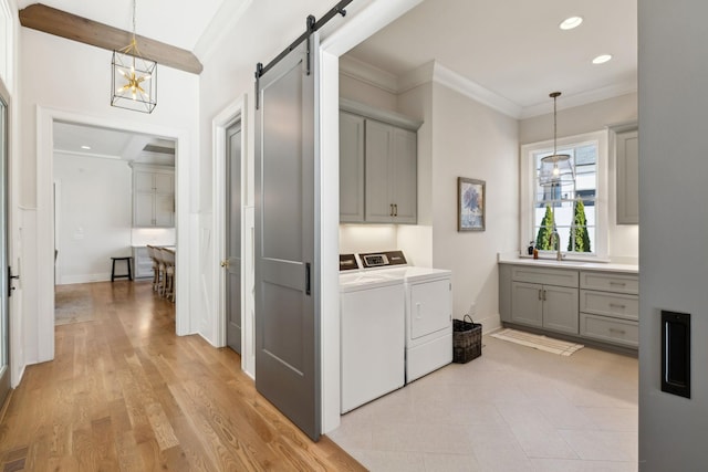 washroom featuring light hardwood / wood-style flooring, cabinets, independent washer and dryer, ornamental molding, and a barn door