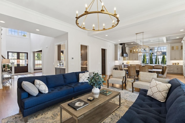 living room with an inviting chandelier, plenty of natural light, light hardwood / wood-style floors, and beamed ceiling