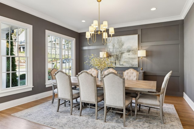 dining area with an inviting chandelier, wood-type flooring, and ornamental molding