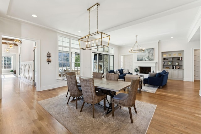 dining area with a notable chandelier, light hardwood / wood-style flooring, and built in features