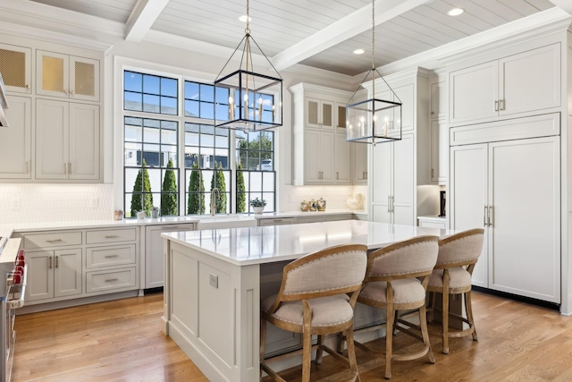 kitchen featuring a kitchen island, pendant lighting, beam ceiling, light hardwood / wood-style floors, and an inviting chandelier