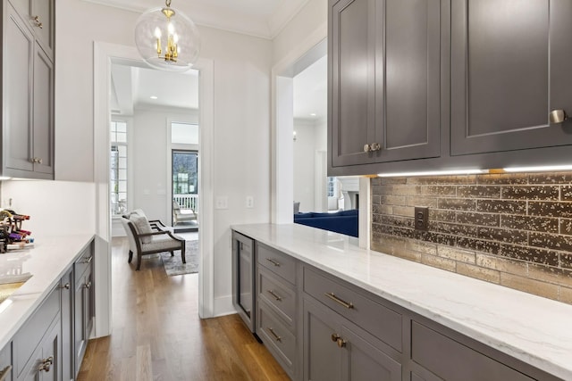 kitchen with decorative light fixtures, gray cabinets, light stone countertops, and light wood-type flooring