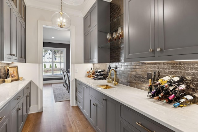 kitchen with gray cabinets, sink, pendant lighting, and light stone counters