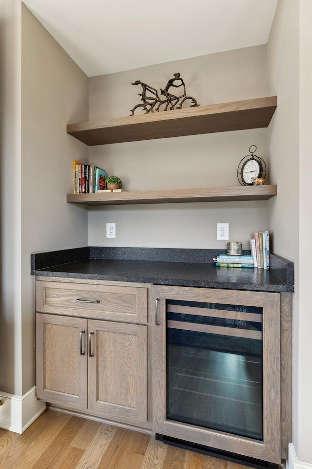 bar featuring beverage cooler, light brown cabinetry, and light wood-type flooring