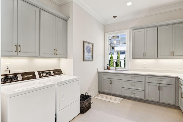 clothes washing area with cabinets, washing machine and dryer, sink, and ornamental molding