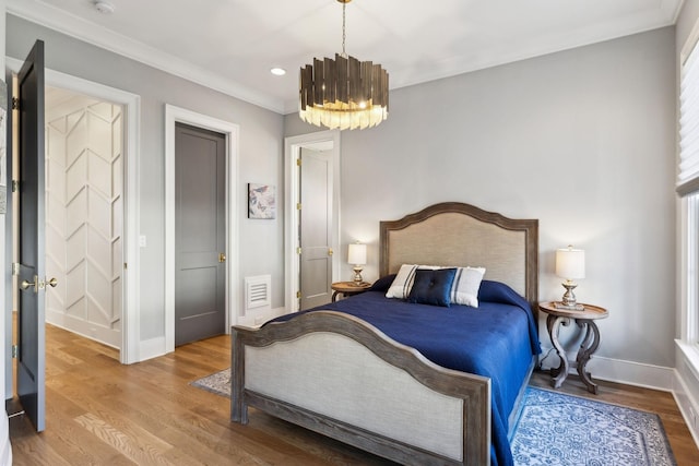 bedroom with an inviting chandelier, ornamental molding, and wood-type flooring