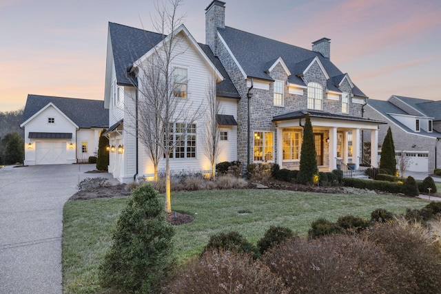 view of front of property with a porch, a garage, and a lawn