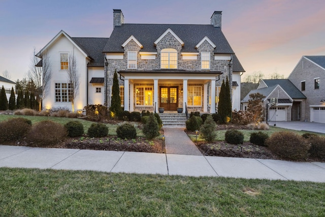 view of front of house featuring a garage, covered porch, and a lawn