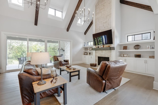 living room with an inviting chandelier, light wood-type flooring, a fireplace, and a high ceiling