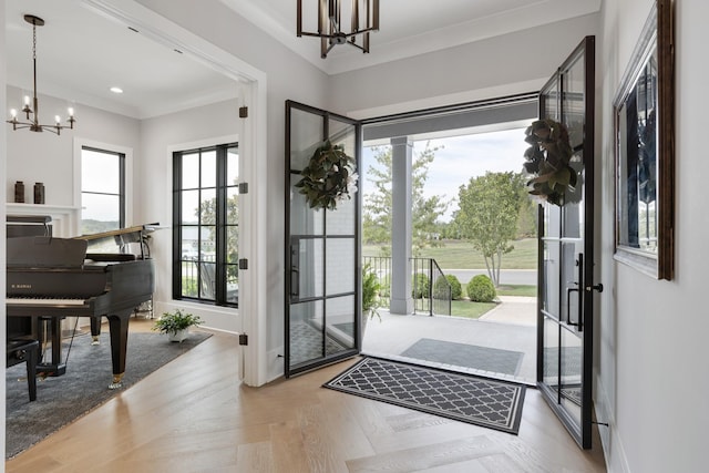 doorway to outside with light parquet flooring, ornamental molding, and a chandelier